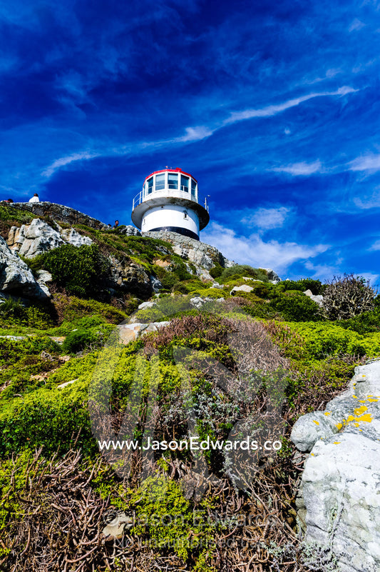 An antique lighthouse summits a cliff near the Cape of Good Hope. Cape of Good Hope, Cape Point, Table Mountain National Park, Cape Peninsula, South Africa.