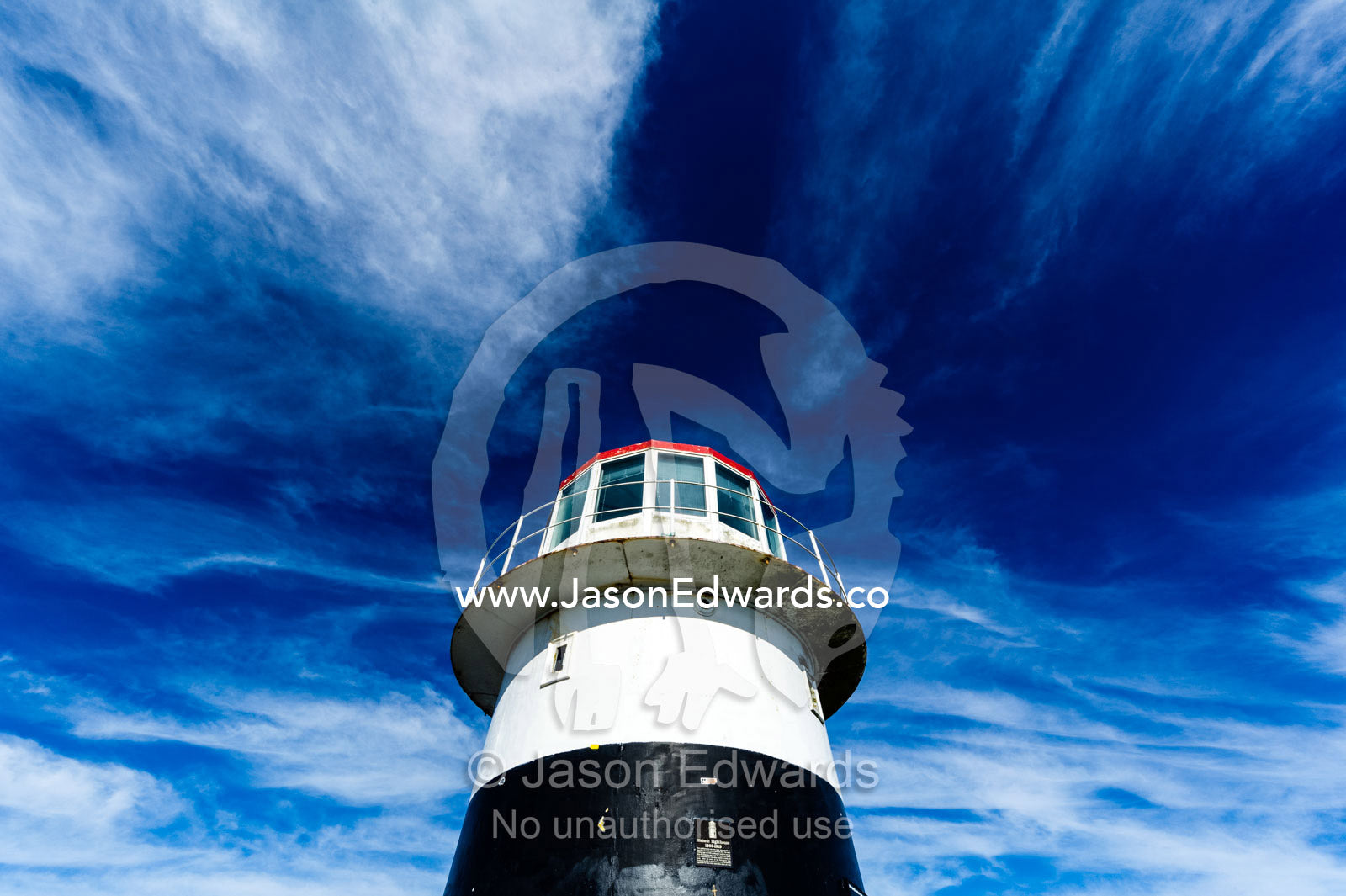 High winds swirl clouds around the pillar of an antique lighthouse. Cape of Good Hope, Cape Point, Table Mountain National Park, Cape Peninsula, South Africa.