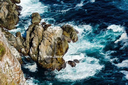 Waves and foam at the base of an ocean cliff. Cape of Good Hope, Cape Point, Table Mountain National Park, Cape Peninsula, South Africa.