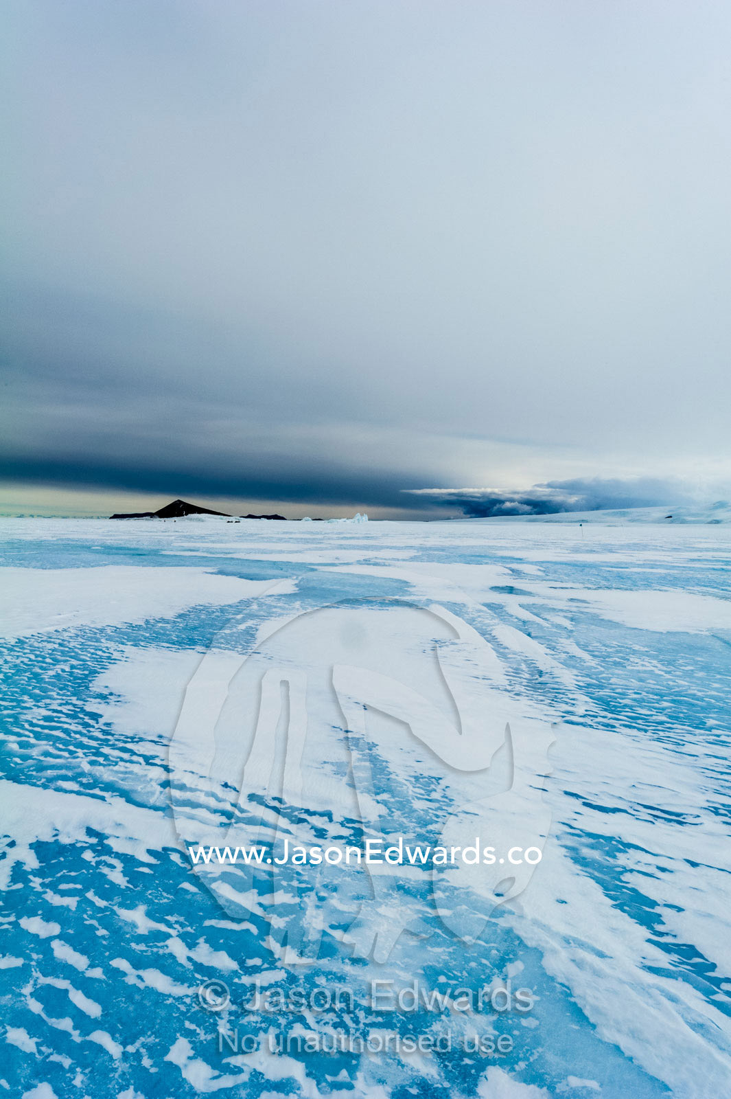 Wind patterns gather in snow drifts on the frozen sea ice in Antarctica. Turtle Rock, Erebus Bay, McMurdo Sound, Ross Island, Antarctica