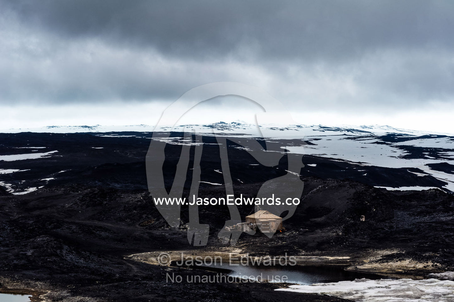 The hut built by Antarctic explorer Ernest Shackleton dwarfed by a harsh and barren landscape. Shackleton's Hut, Cape Royds, Ross Island, Antarctica.