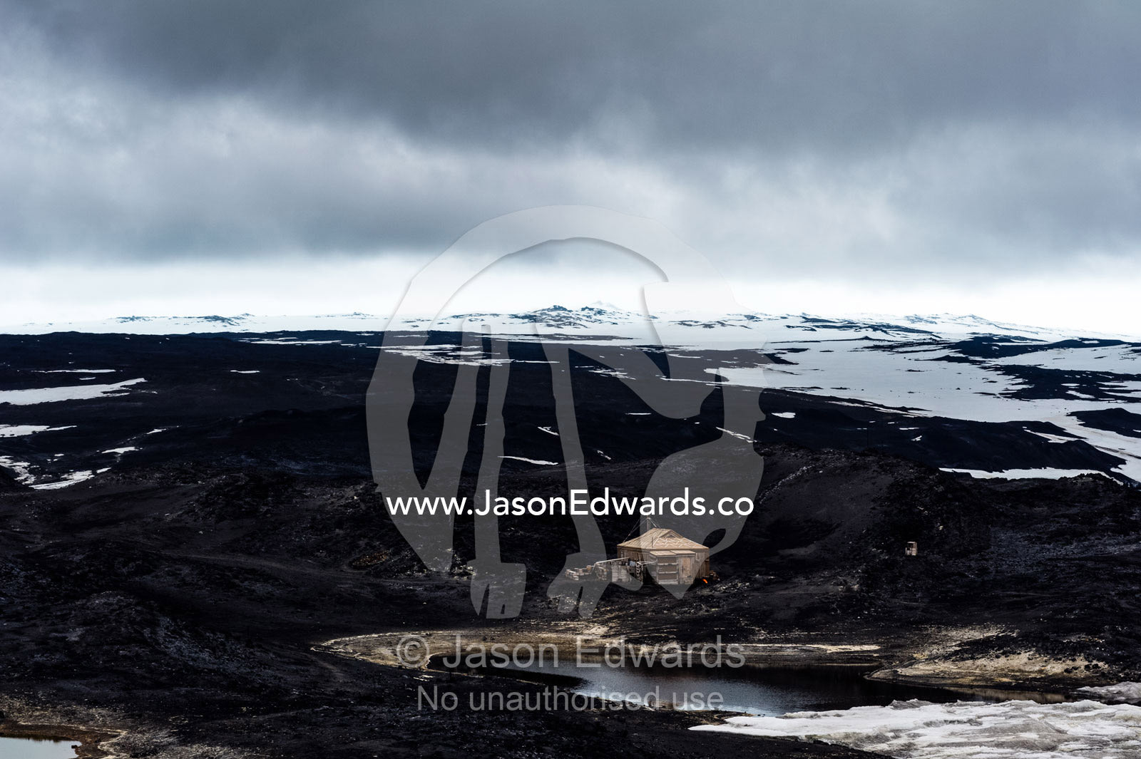The hut built by Antarctic explorer Ernest Shackleton dwarfed by a harsh and barren landscape. Shackleton's Hut, Cape Royds, Ross Island, Antarctica.