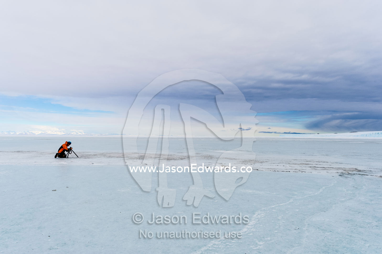 A cameraman filming on the sea ice in Antarctica. Scott's Hut, Cape Evans, North Bay, Ross Island, Antarctica.