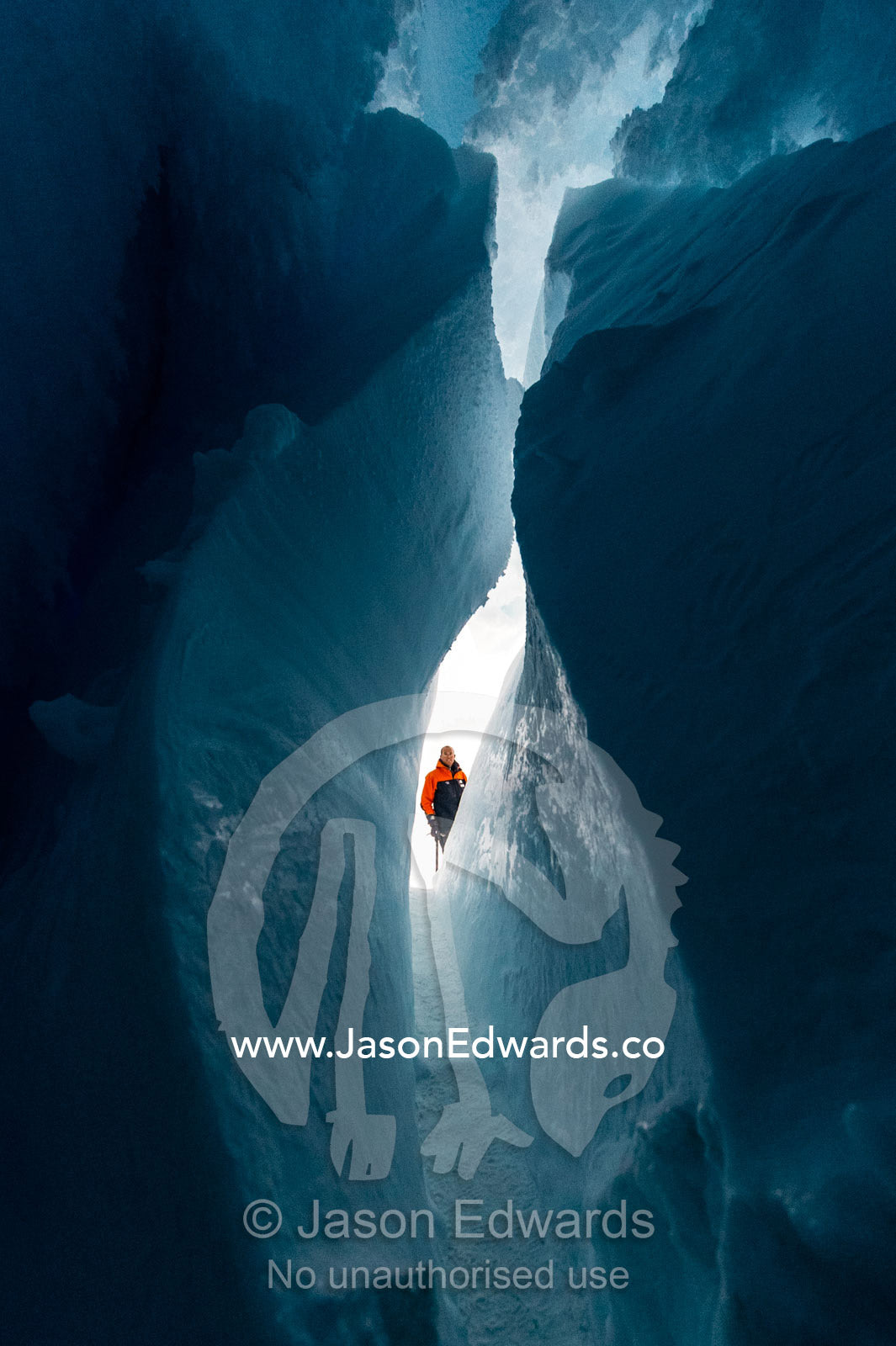 An ice guide examines the frozen ceiling and icy walls of an ice cave in the Erebus Glacier Tongue. Erebus Ice Caves, Mount Erebus, Ross Island, Antarctica.