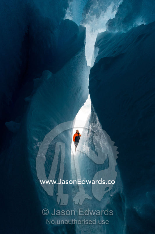 An ice guide examines the frozen ceiling and icy walls of an ice cave in the Erebus Glacier Tongue. Erebus Ice Caves, Mount Erebus, Ross Island, Antarctica.