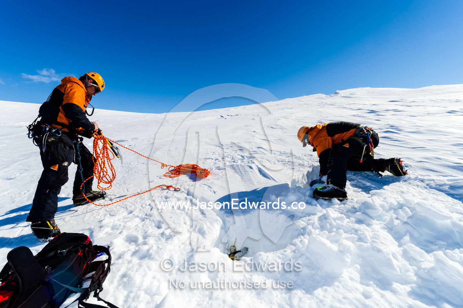 Ice guides digging snow anchors to hold ropes to enter a crevasse on the slopes of Mount Erebus in Antarctica. Silver City Ice Fall, Hut Point Peninsula, Ross Island Antarctica.