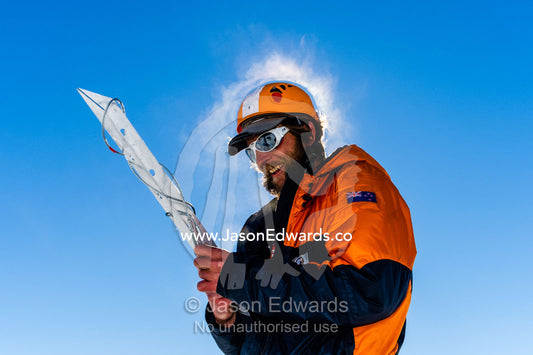 Steam rises from the head of an ice guide preparing a snow anchor to enter a crevasse on the slopes of Mount Erebus in Antarctica. Silver City Ice Fall, Hut Point Peninsula, Ross Island Antarctica.