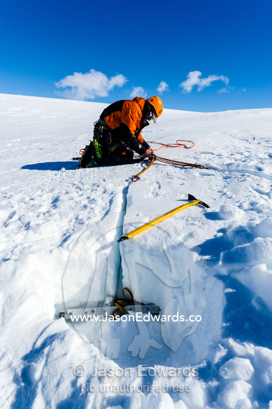 Ice guides digging snow anchors to hold ropes to enter a crevasse on the slopes of Mount Erebus in Antarctica. Silver City Ice Fall, Hut Point Peninsula, Ross Island Antarctica.