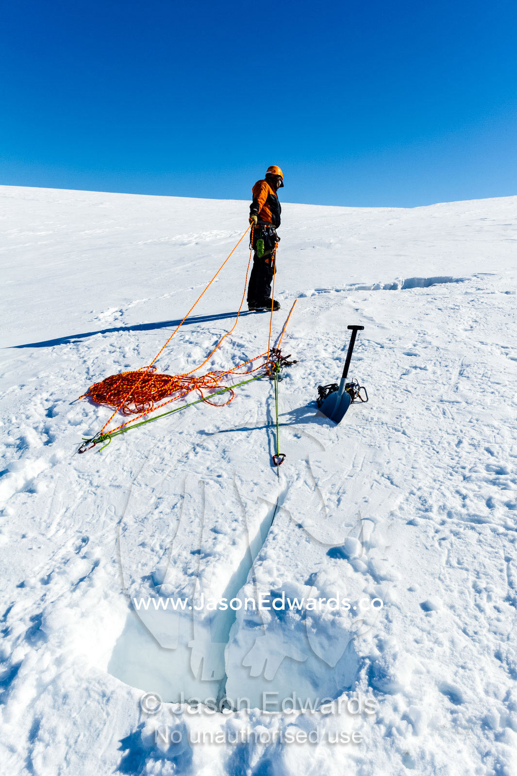 Ice guides digging snow anchors to hold ropes to enter a crevasse on the slopes of Mount Erebus in Antarctica. Silver City Ice Fall, Hut Point Peninsula, Ross Island Antarctica.