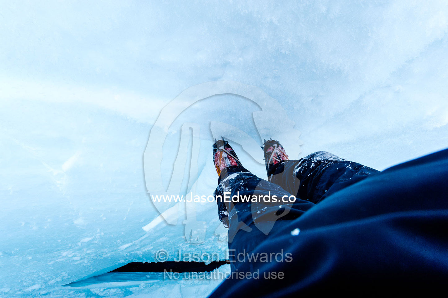 A photographer descending the sheer icy walls of a crevasse on the slopes of Mount Erebus in Antarctica. Silver City Ice Fall, Hut Point Peninsula, Ross Island Antarctica.