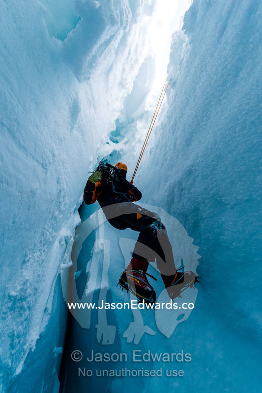 A cameraman filming from the sheer icy walls of a crevasse on the slopes of Mount Erebus in Antarctica. Silver City Ice Fall, Hut Point Peninsula, Ross Island Antarctica.