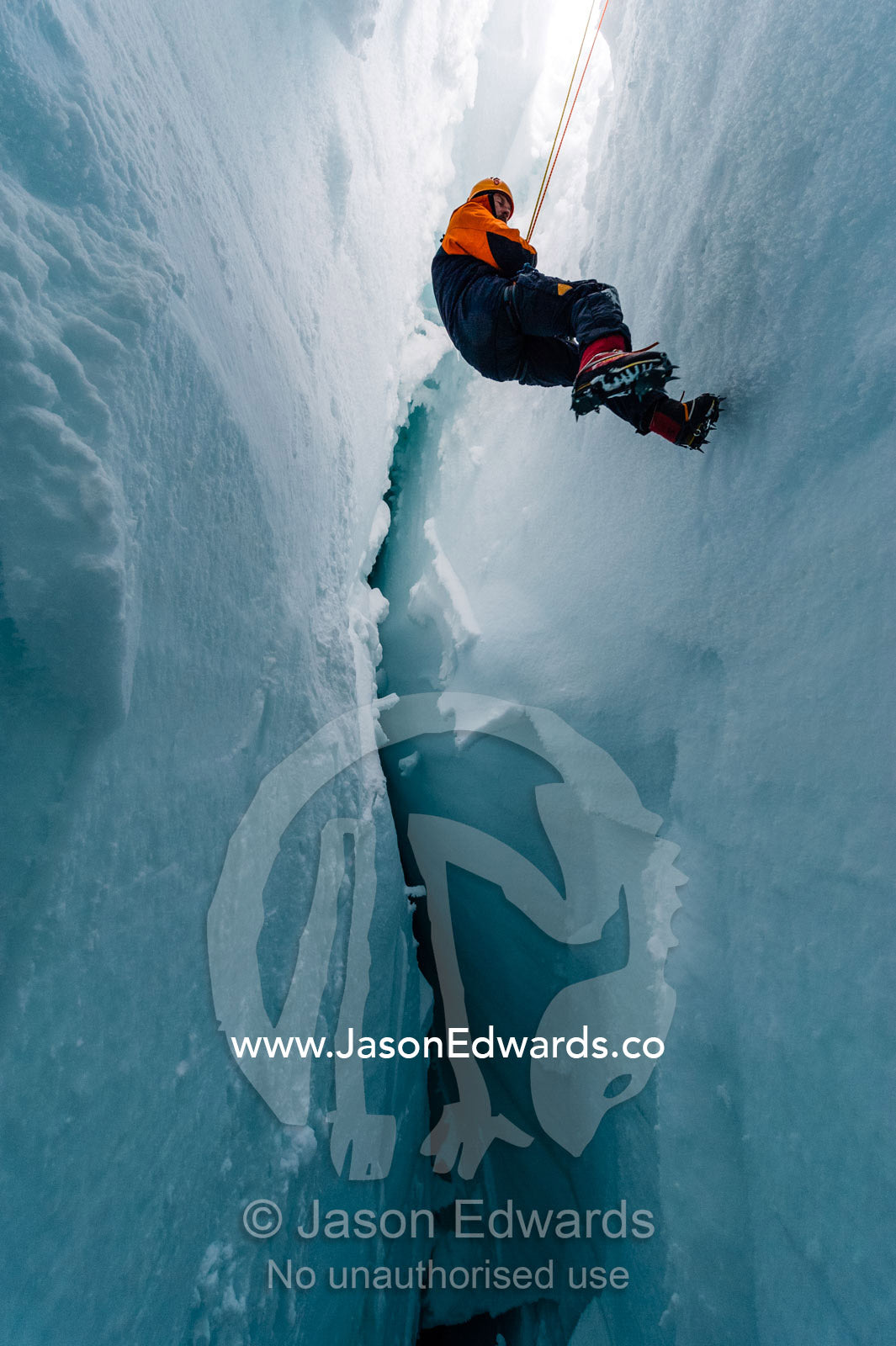 A cameraman descending the sheer icy walls of a crevasse on the slopes of Mount Erebus in Antarctica. Silver City Ice Fall, Hut Point Peninsula, Ross Island Antarctica.