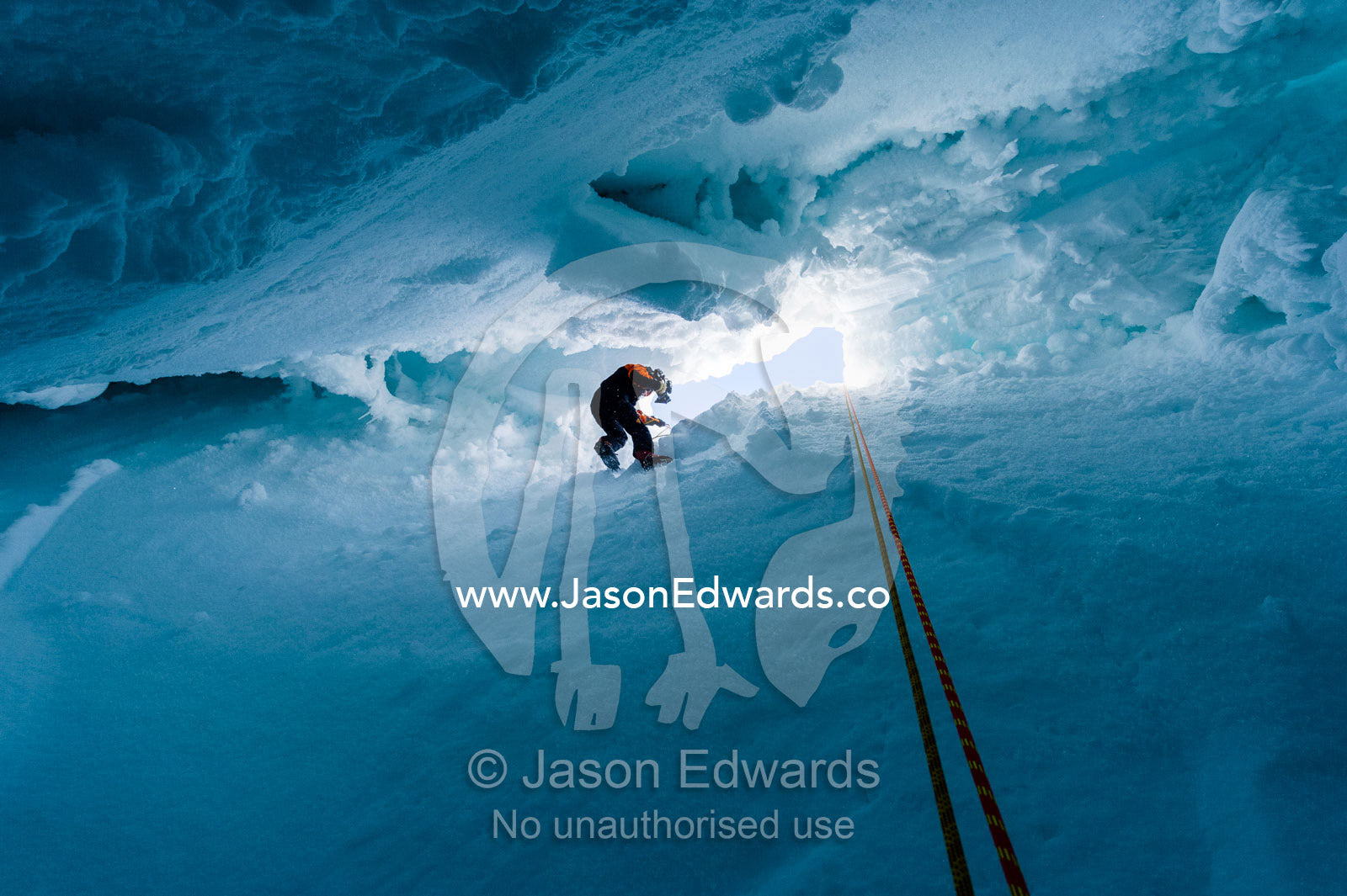 A cameraman descending the sheer icy walls of a crevasse on the slopes of Mount Erebus in Antarctica. Silver City Ice Fall, Hut Point Peninsula, Ross Island Antarctica.