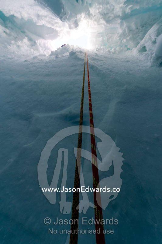 Ropes descending into the entrance of a crevasse on the slopes of Mount Erebus in Antarctica. Silver City Ice Fall, Hut Point Peninsula, Ross Island Antarctica.