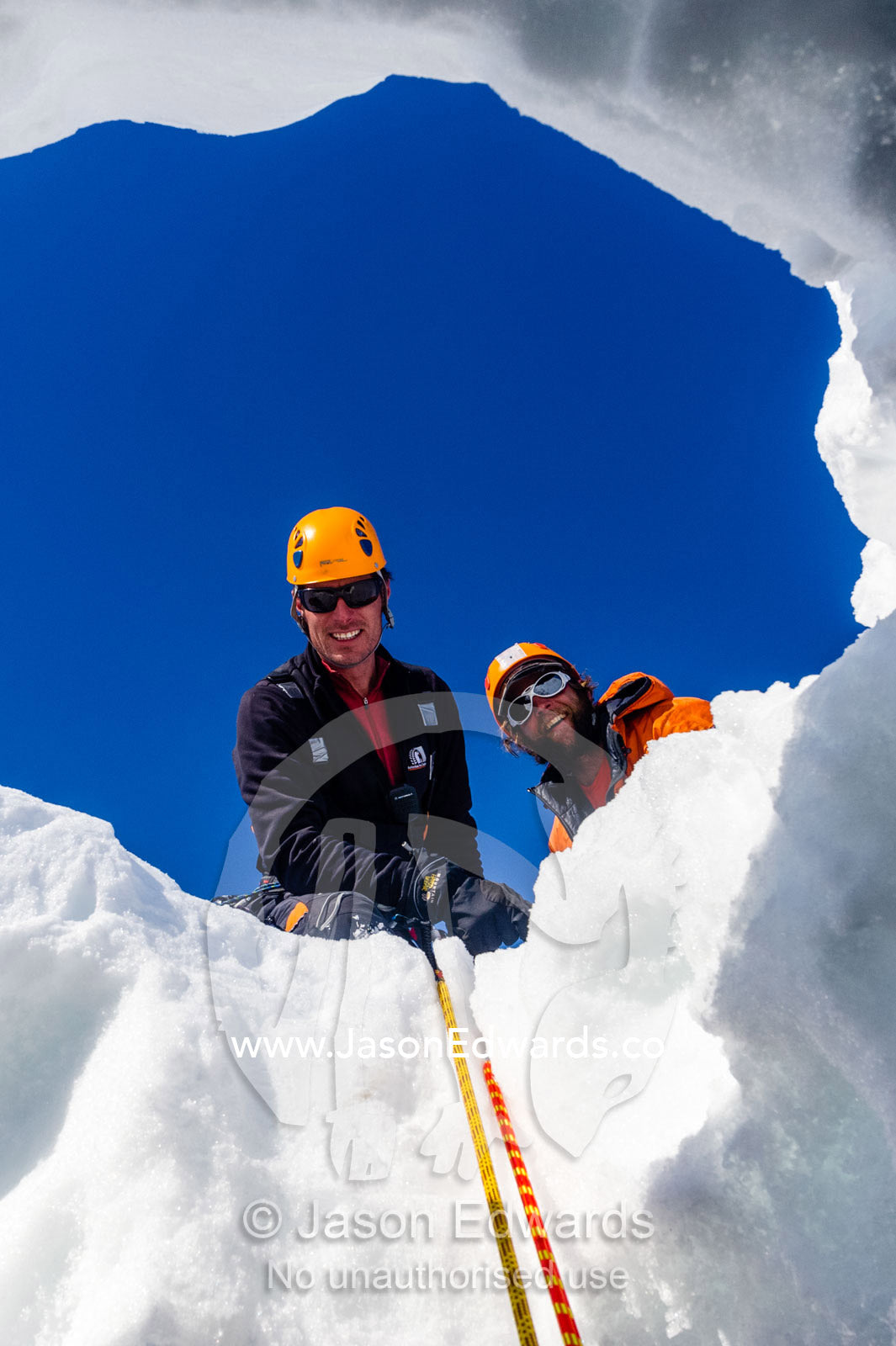Ice guides peering into a crevasse on the slopes of Mount Erebus in Antarctica. Silver City Ice Fall, Hut Point Peninsula, Ross Island Antarctica.