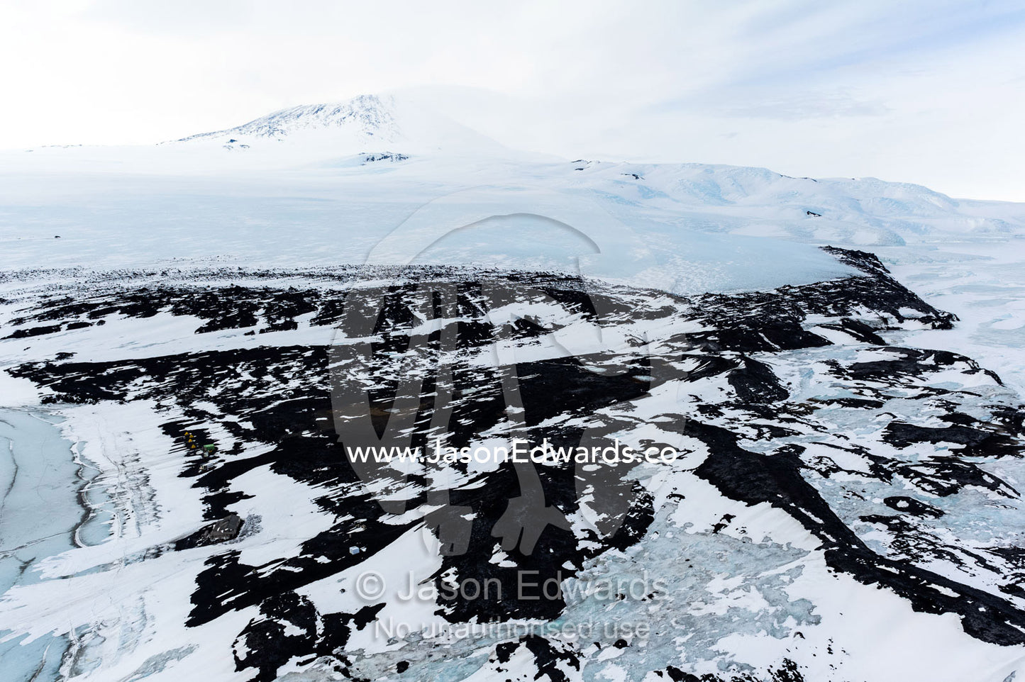 An aerial view of Antarctic explorer Robert Falcon Scott's Hut on the shore of the sea ice. Scott's Hut, Mount Erebus, Cape Evans, McMurdo Sound, Ross Island, Antarctica.