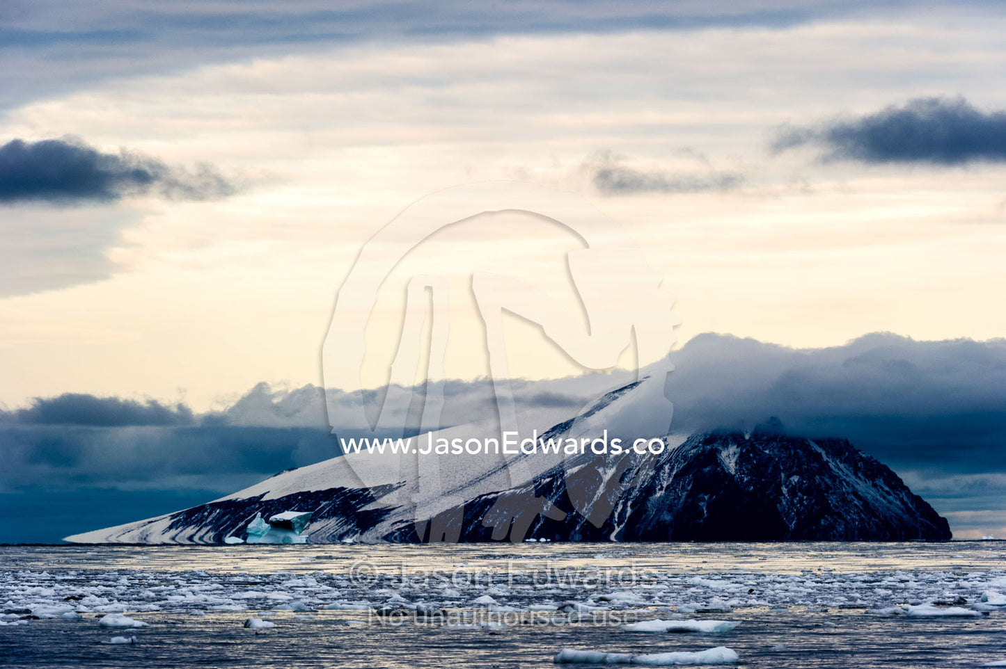 The ice-covered summit of an island rises from the sea in Antarctica. Beaufort Island, Cape Bird, Ross Island, Antarctica.