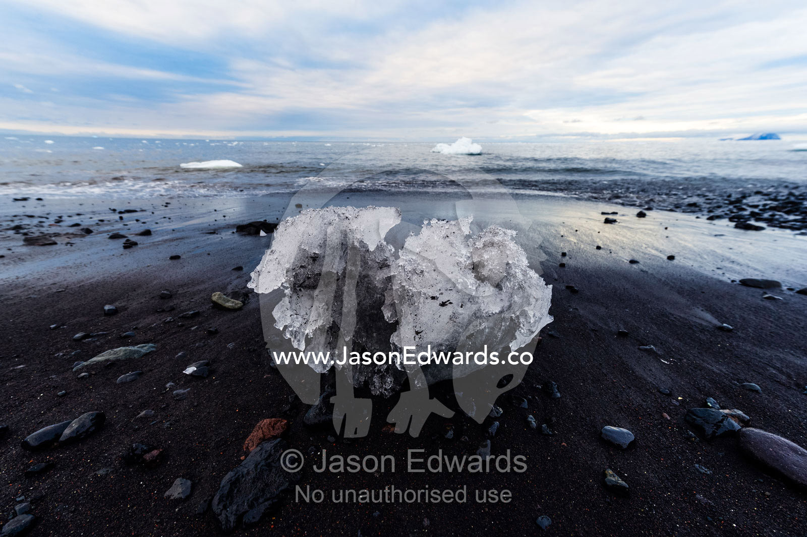 A boulder of glacier ice resting on a black volcanic beach in Antarctica. Caughley Beach, Cape Bird, Ross Island, Antarctica.