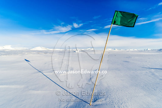 A green flag highlights a safe route across the sea ice. Pram Point, McMurdo Sound, Ross Island, Antarctica.
