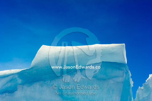 Enormous blocks of backlit ice are pushed skyward along pressure ridges as the sea ice thins and forms melt pools. Pram Point, McMurdo Sound, Ross Island, Antarctica.