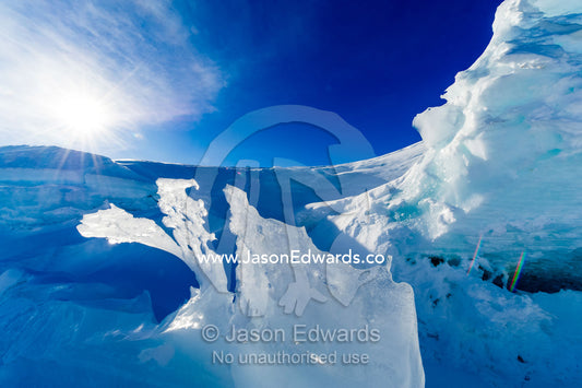 The sculptured jagged edge of a sea ice pressure ridge backlit by the sun. Pram Point, McMurdo Sound, Ross Island, Antarctica.