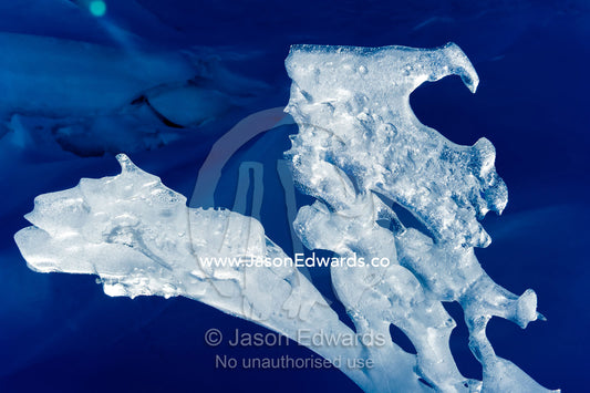 The sculptured jagged edge of a sea ice pressure ridge backlit by the sun. Pram Point, McMurdo Sound, Ross Island, Antarctica.