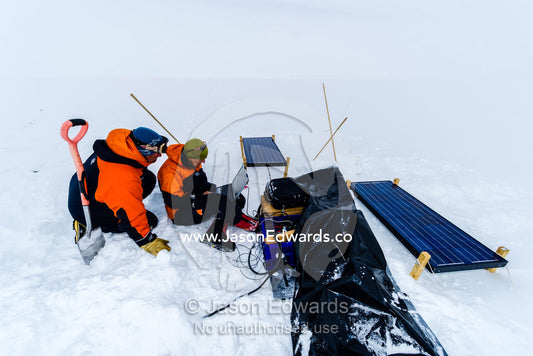 Volcanologists on a frozen plain monitor a volcano research sensor with a laptop computer. Windless Bight, Hut Point Peninsula, Ross Island, Antarctica.
