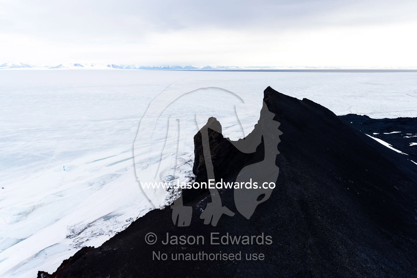 Jagged volcanic peaks overlooking a vast horizon of sea ice. The Pillar, Cape Barne, Ross Island, Antarctica.