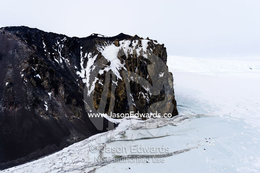 Pressure ridges in the sea ice crack against sheer rocky cliffs in Antarctica. Turks Head, Turks Head Bay, Ross Island, Antarctica.