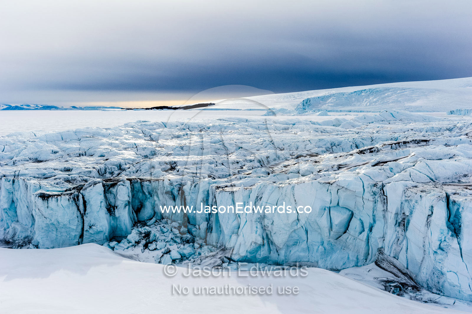 The sheer impregnable ice cliffs of a glacier tower over the frozen sea ice. Lands End, South Bay, Ross Island, Antarctica.