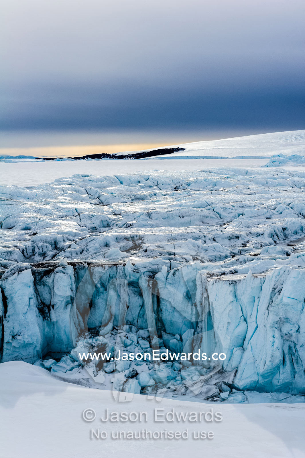 The sheer impregnable ice cliffs of a glacier tower over the frozen sea ice. Lands End, South Bay, Ross Island, Antarctica.