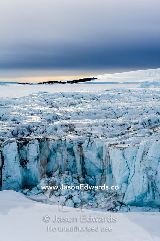 The sheer impregnable ice cliffs of a glacier tower over the frozen sea ice. Lands End, South Bay, Ross Island, Antarctica.