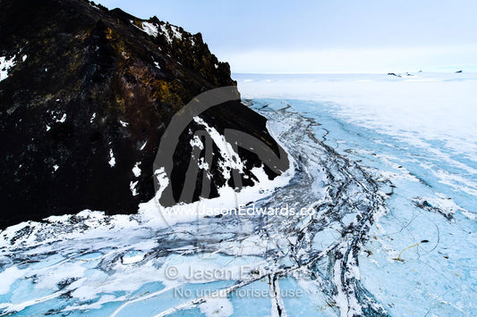 Pressure ridges in the sea ice crack against sheer rocky cliffs in Antarctica. Turks Head, Turks Head Bay, Ross Island, Antarctica.