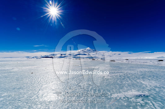 The polished surface of the sea ice blown clear of snow by strong winds. Hutton Cliffs, Erebus Bay, McMurdo Sound, Ross Island, Antarctica.