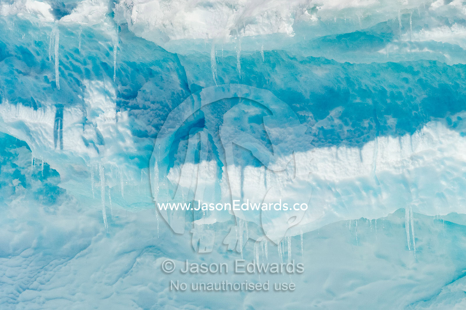 Blue icicles hang from a jagged cliff face and cave entrance. Hutton Cliffs, Erebus Bay, McMurdo Sound, Ross Island, Antarctica.
