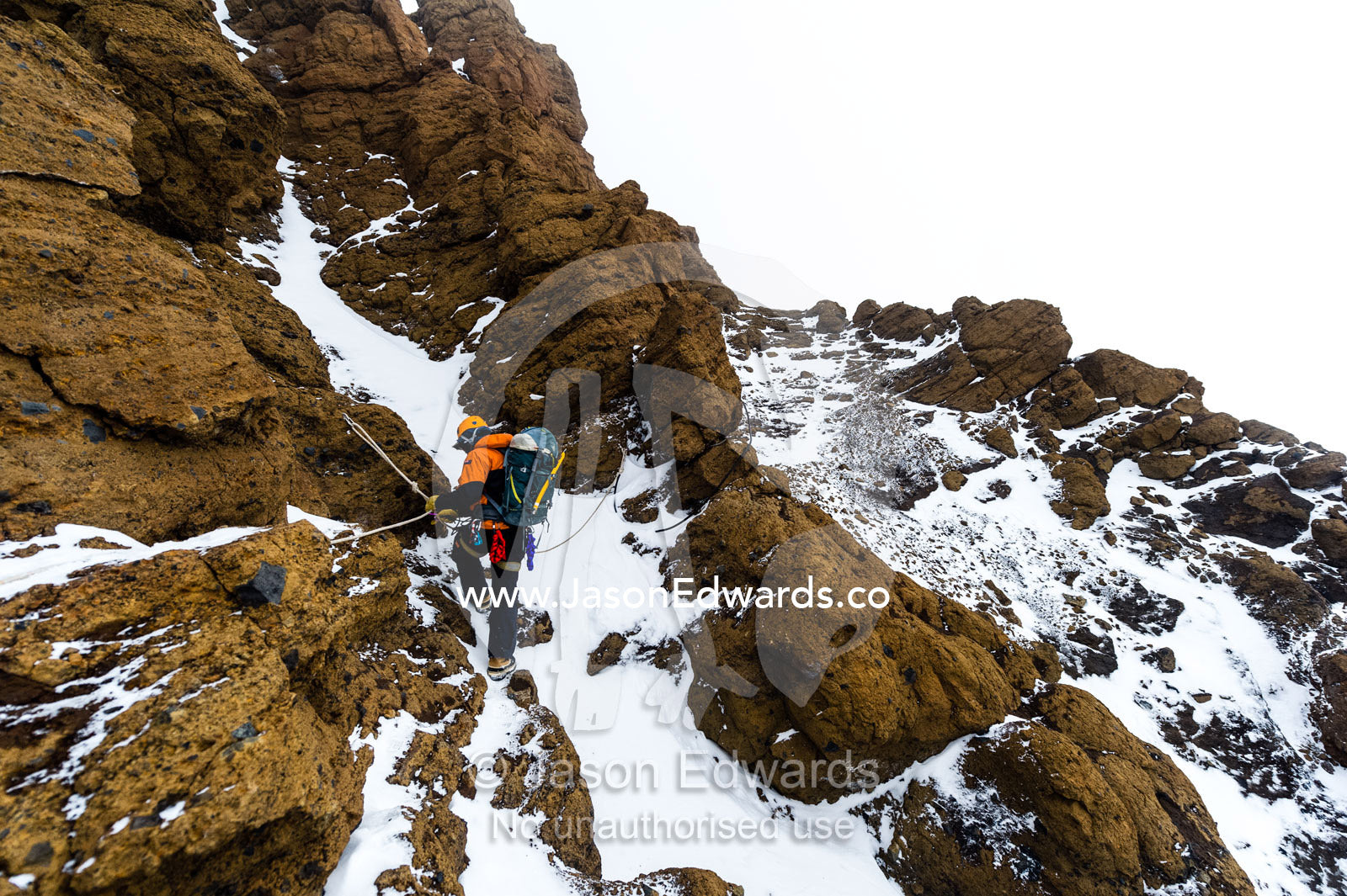 Mountain climbers using climbing ropes to scale a cliff overlooking the Ross Ice Shelf. Castle Rock, Hut Point Peninsula, Ross Island, Antarctica.