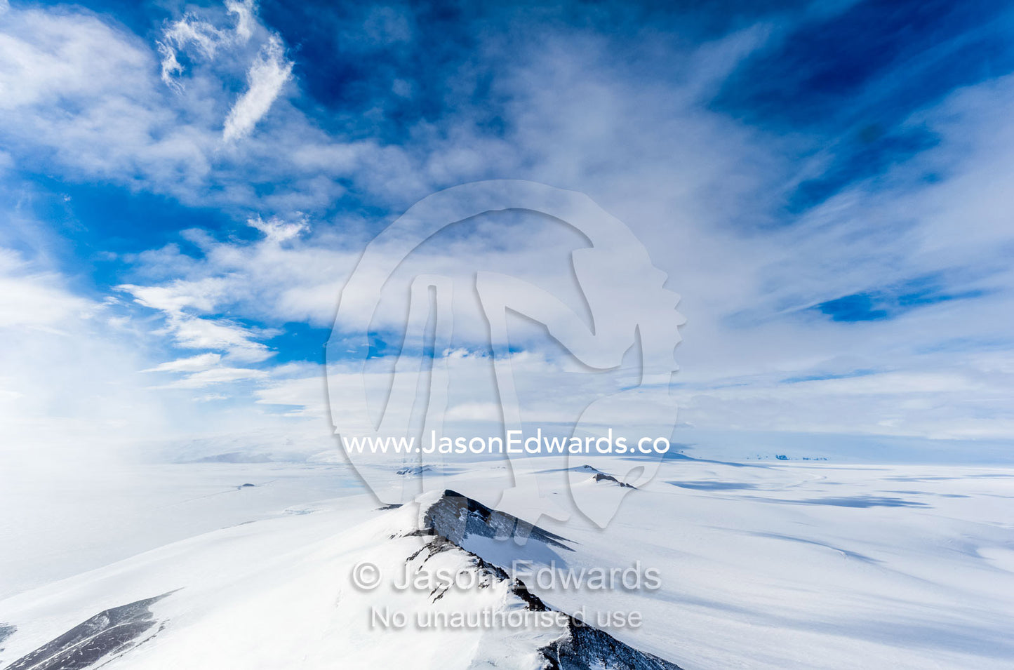 A snow-covered mountain ridge overlooking Mount Erebus an active volcano. Breached Cone, Hut Point Peninsula, Ross Island, Antarctica.