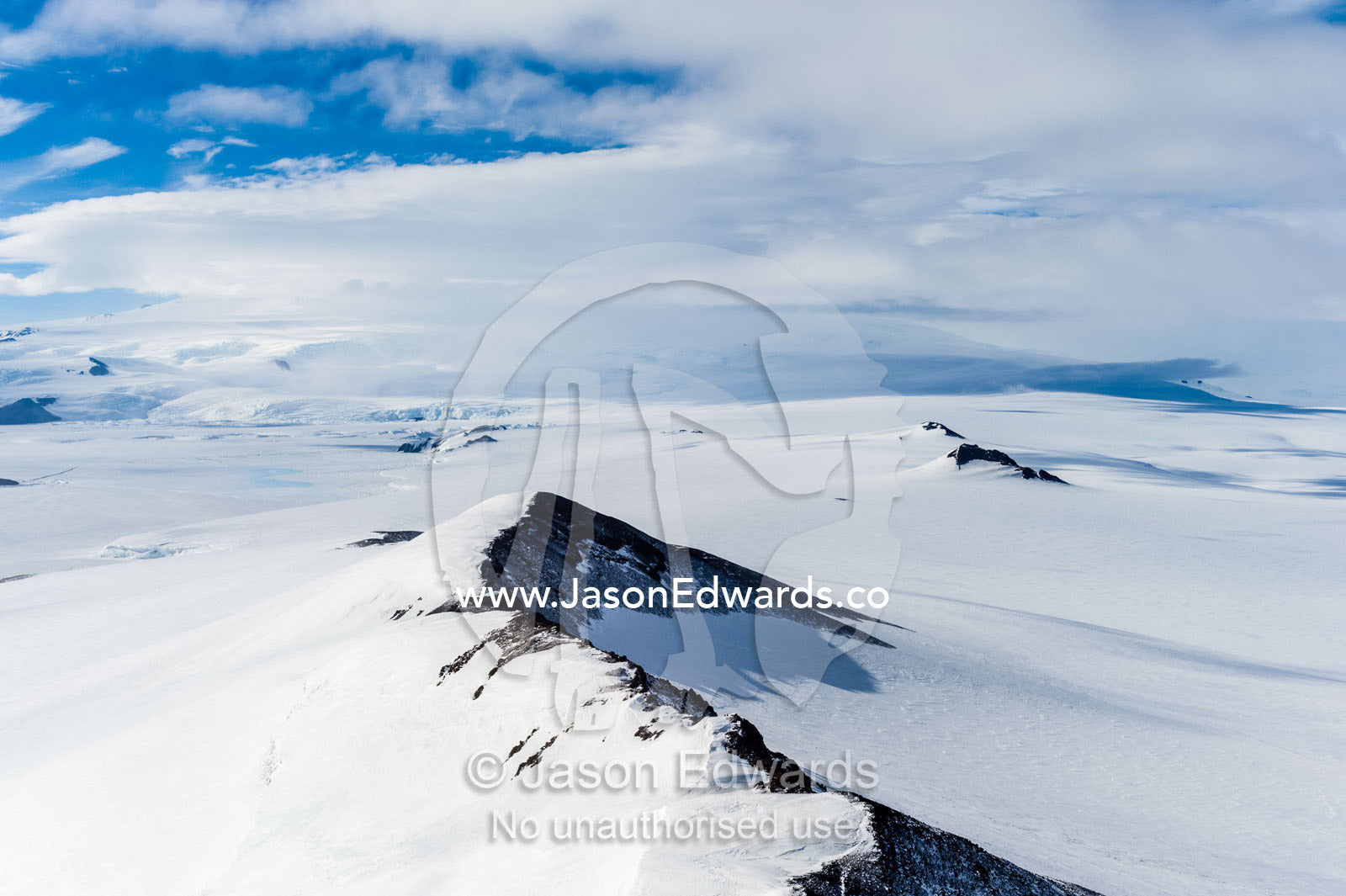 A snow-covered mountain ridge overlooking Mount Erebus an active volcano. Breached Cone, Hut Point Peninsula, Ross Island, Antarctica.