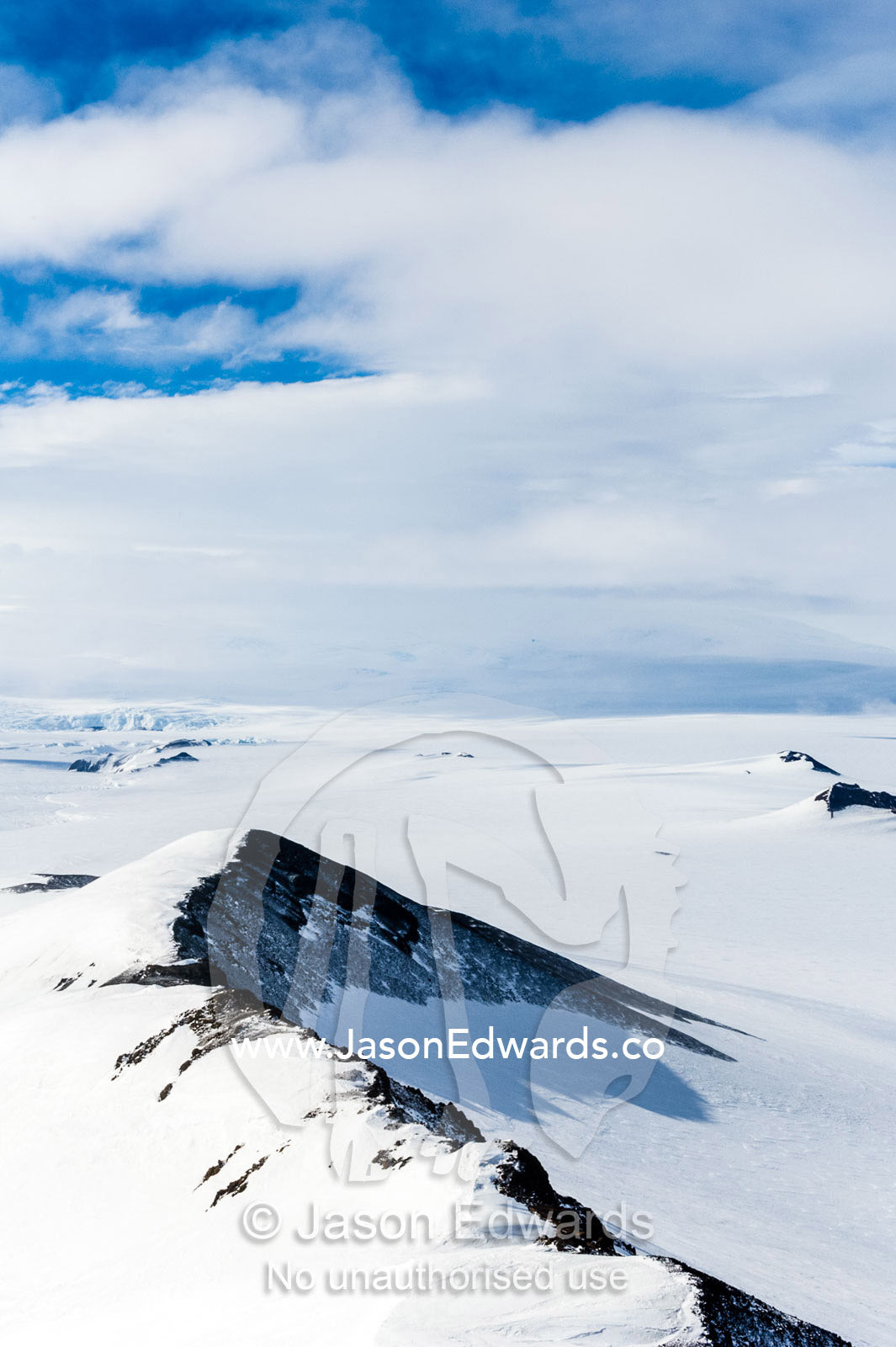 A snow-covered mountain ridge overlooking Mount Erebus an active volcano. Breached Cone, Hut Point Peninsula, Ross Island, Antarctica.