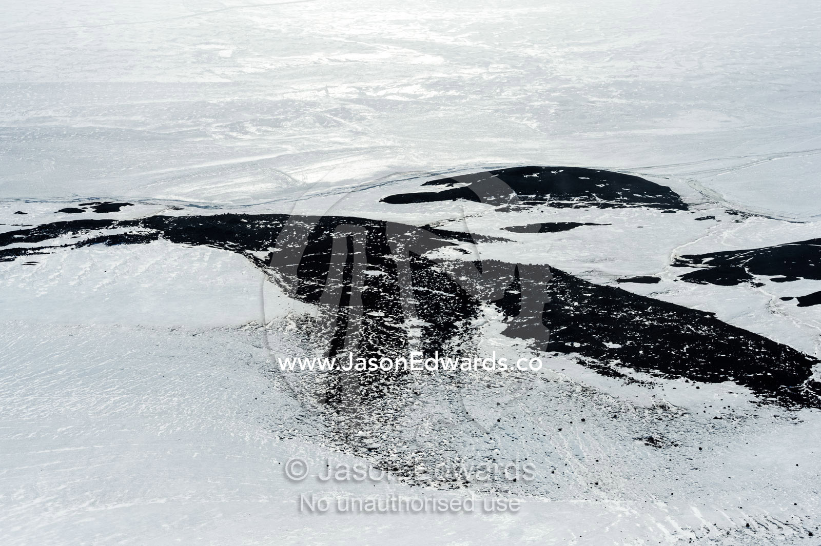Ice and snow cover a rocky shore on the Ross Sea. McMurdo Sound, Ross Island, Antarctica.