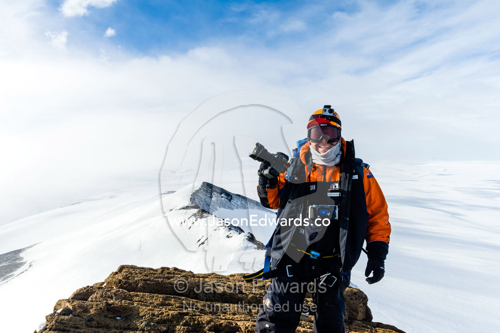 A photographer standing with his camera on a mountaintop in Antarctica. Breached Cone, Castle Rock, Hut Point Peninsula, Ross Island, Antarctica.