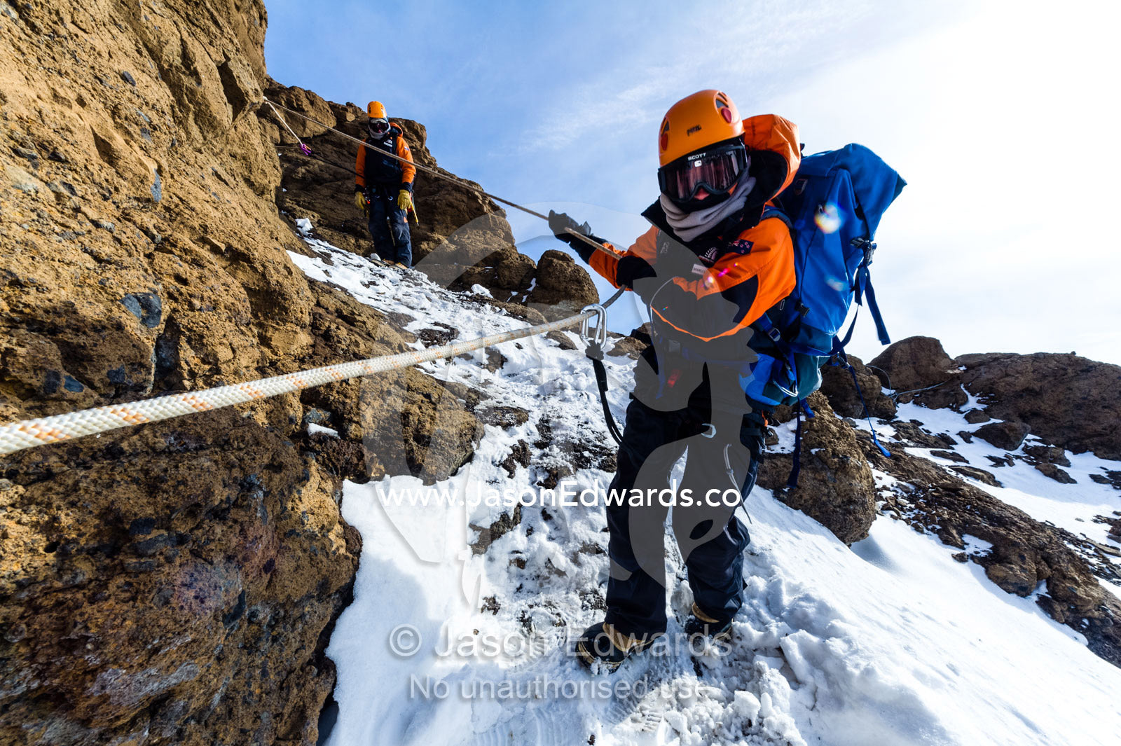 Mountain climbers using climbing ropes and carabiner to scale a cliff overlooking the Ross Ice Shelf. Castle Rock, Hut Point Peninsula, Ross Island, Antarctica.
