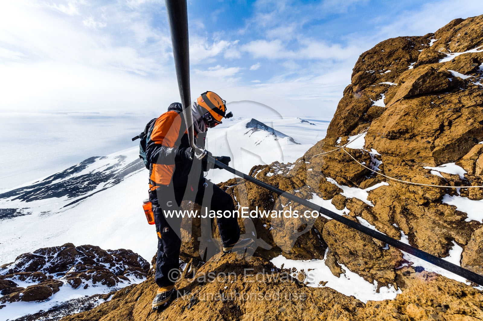 Mountain climbers using climbing ropes and carabiner to scale a cliff overlooking the Ross Ice Shelf. Castle Rock, Hut Point Peninsula, Ross Island, Antarctica.