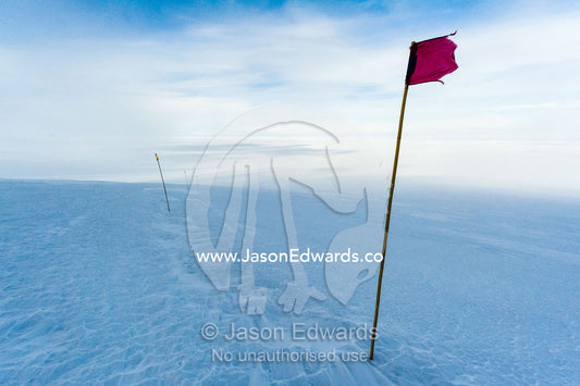 A red flag highlights a safe route across the sea ice. Castle Rock Road, Hut Point Peninsula, Ross Island, Antarctica.