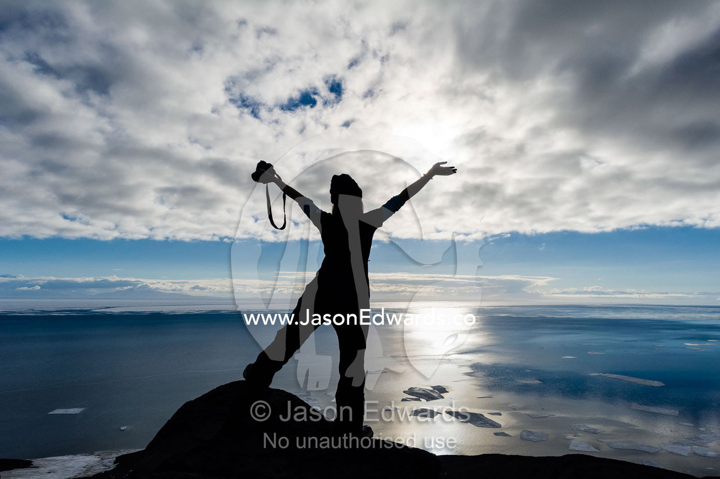 The silhouette of a woman throwing her arms up in joy in Antarctica. Observation Hill, McMurdo Sound, Ross Island, Antarctica.