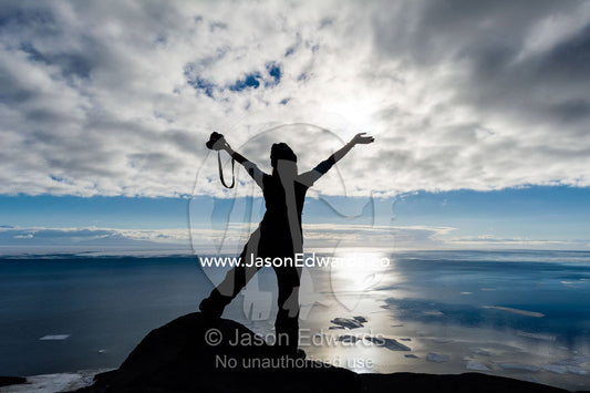 The silhouette of a woman throwing her arms up in joy in Antarctica. Observation Hill, McMurdo Sound, Ross Island, Antarctica.
