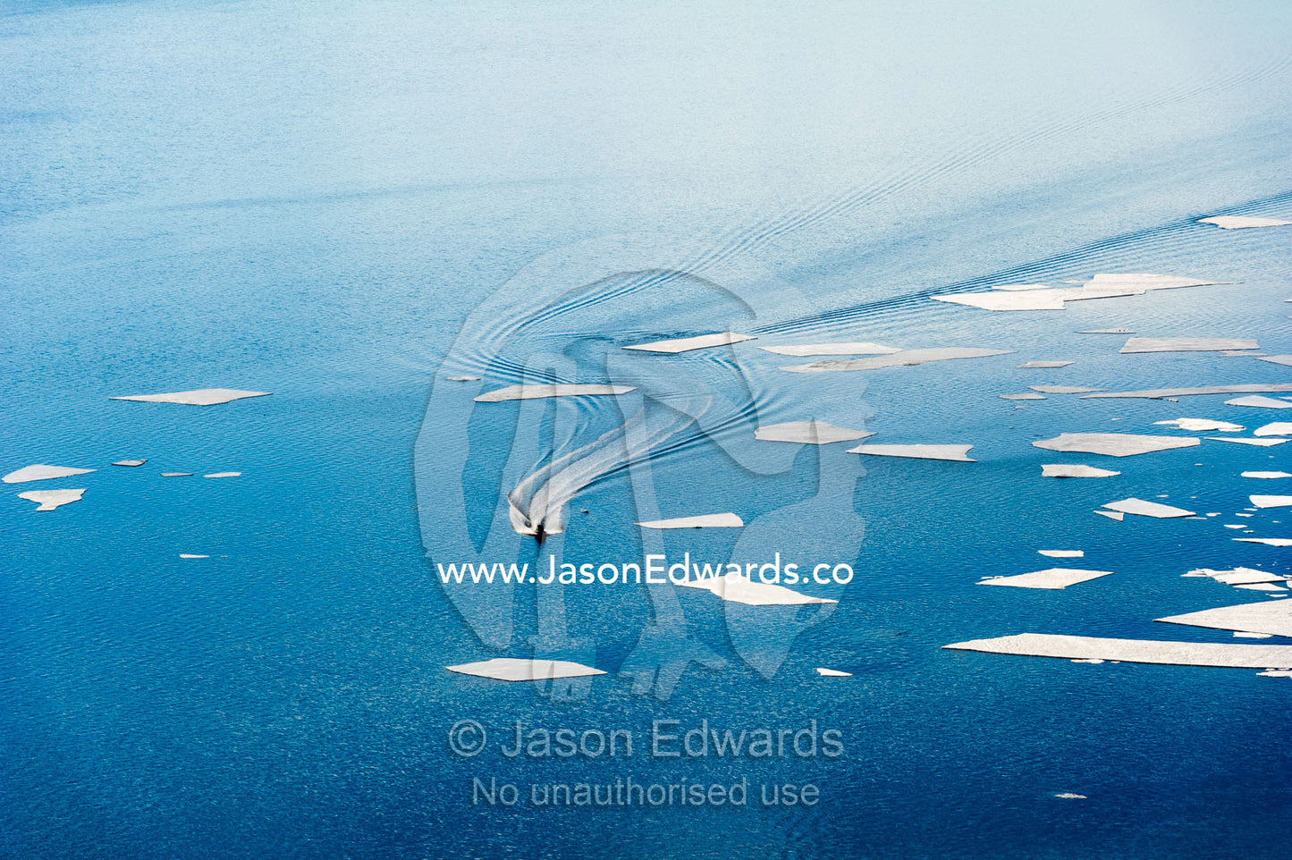 An inflatable zodiac transports sailors from a US naval vessel through sea ice that is breaking up. McMurdo Sound, McMurdo Station, Ross Island, Antarctica.