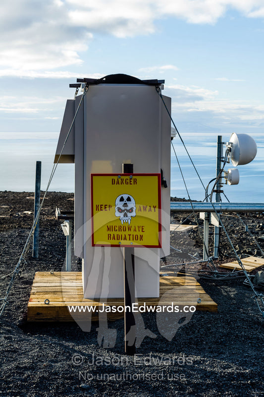 Skull and fang warning signs at a dangerous microwave radiation research site. McMurdo Station, Ross Island, Antarctica.