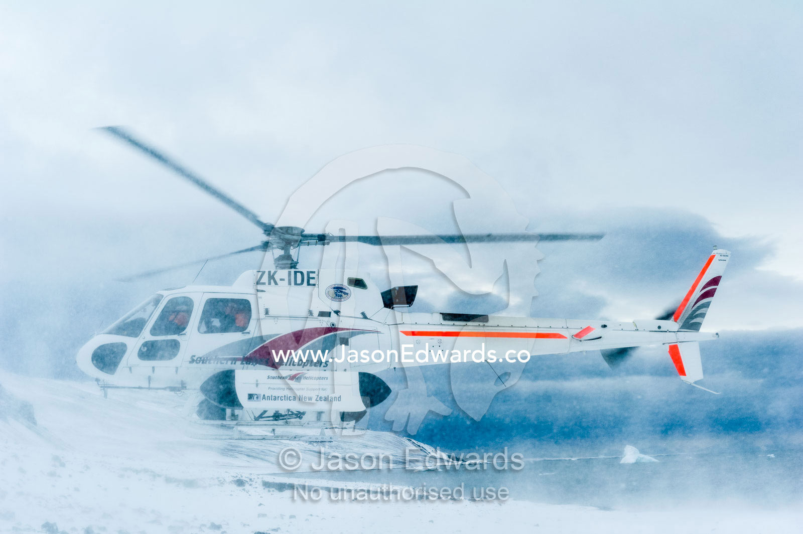 A helicopter blasts snow in the air landing on a beach in Antarctica. Caughley Beach, Cape Bird, Ross Island, Antarctica.