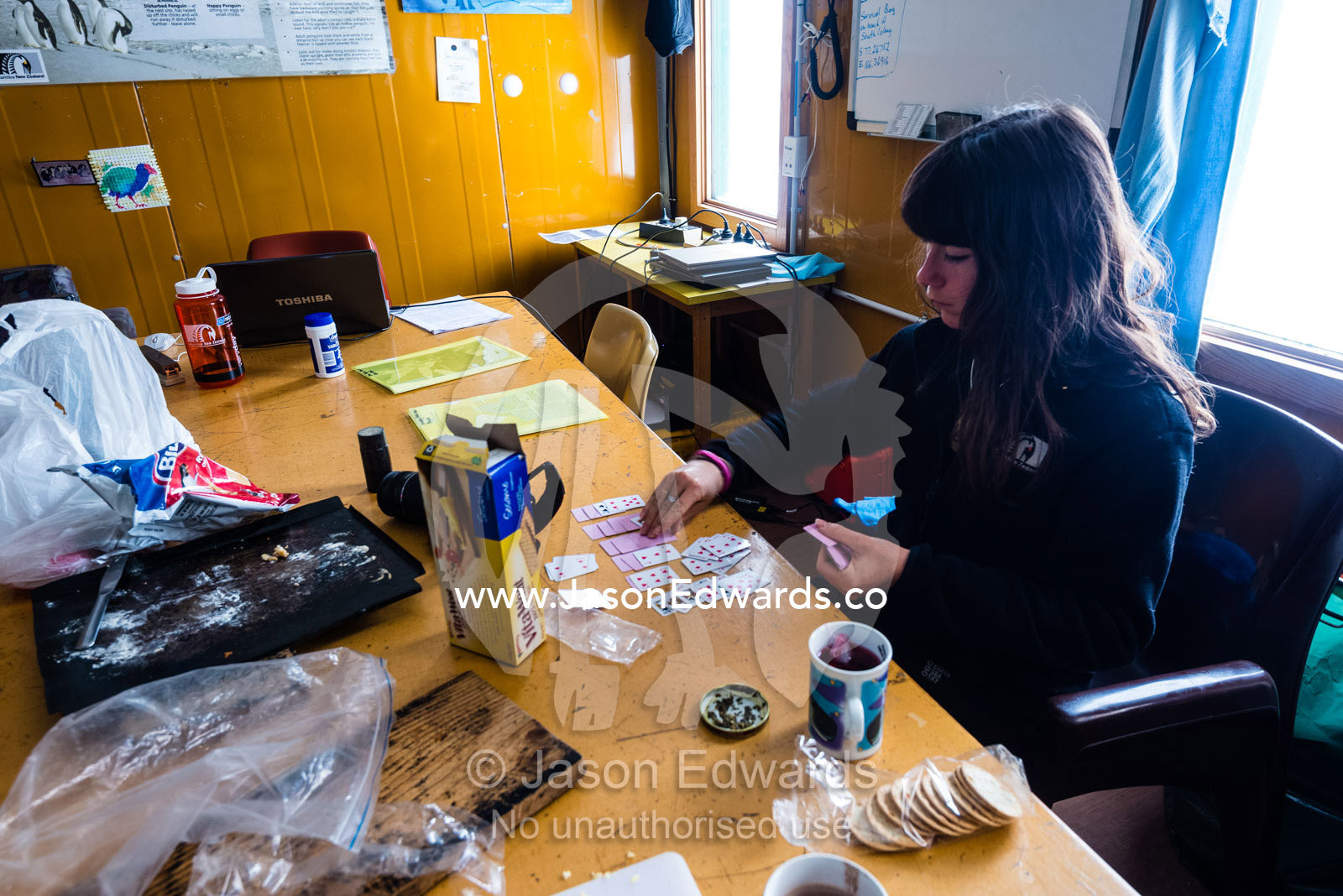 A volunteer plays cards to pass the time in a remote research station in Antarctica. Cape Bird, Ross Island, Antarctica.